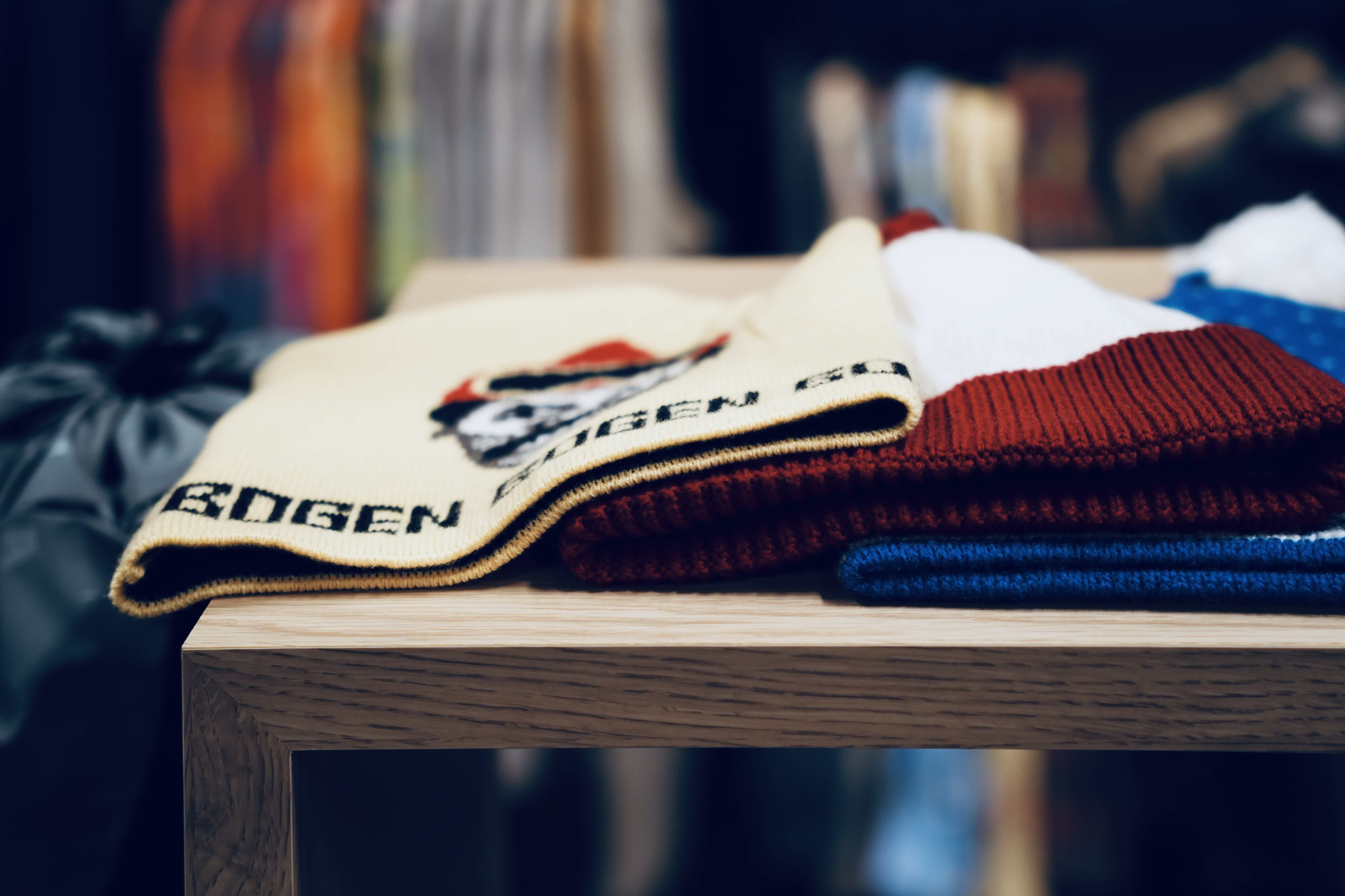 Stack of colorful sweaters on a wooden table in a clothing store.
