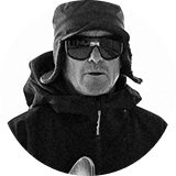 Person wearing sunglasses and a hat, standing outdoors in a snowy environment.