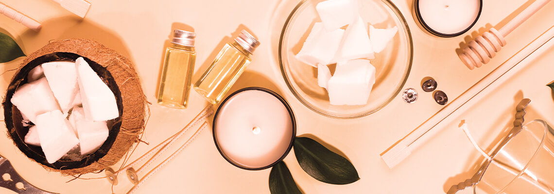 Flat lay of skincare products and candles on a pastel background.