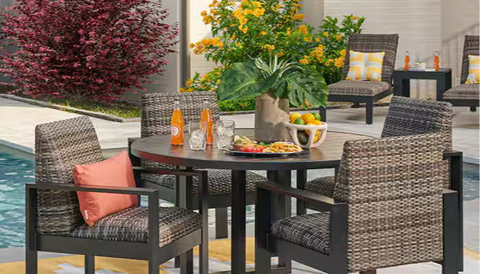 Outdoor dining set with chairs, table, and drinks by a pool.
