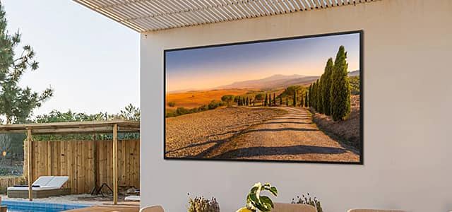 A scenic landscape displayed on a wall-mounted television outdoors.