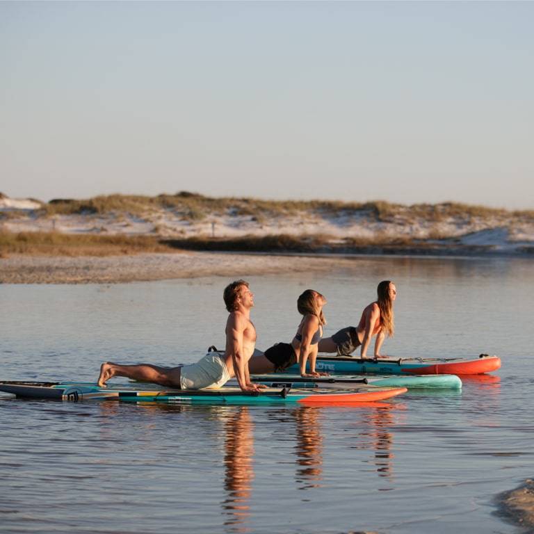 Friends practicing yoga on their BOTE paddle boards
