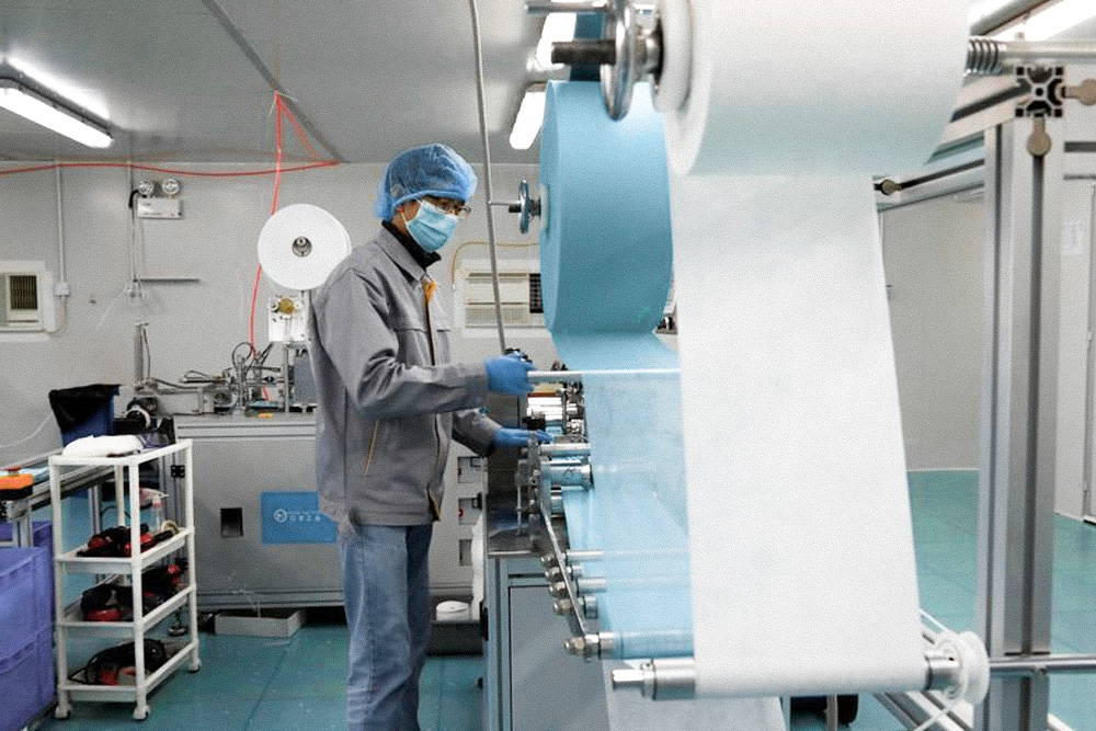 Trabajador de fabricación de mascarilla en sala blanca