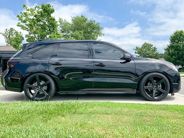 Side profile Carrie's black 2017 Acura MDX with chrome delete and black wheels on driveway photo 2