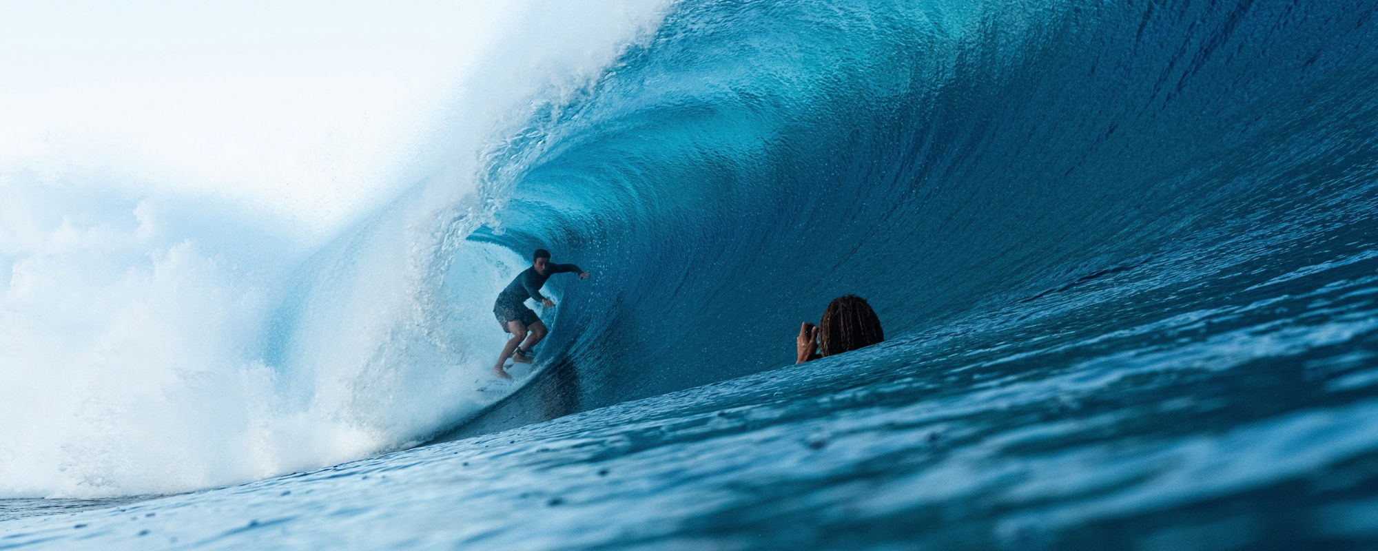 Surfer riding a wave with another person in the water.