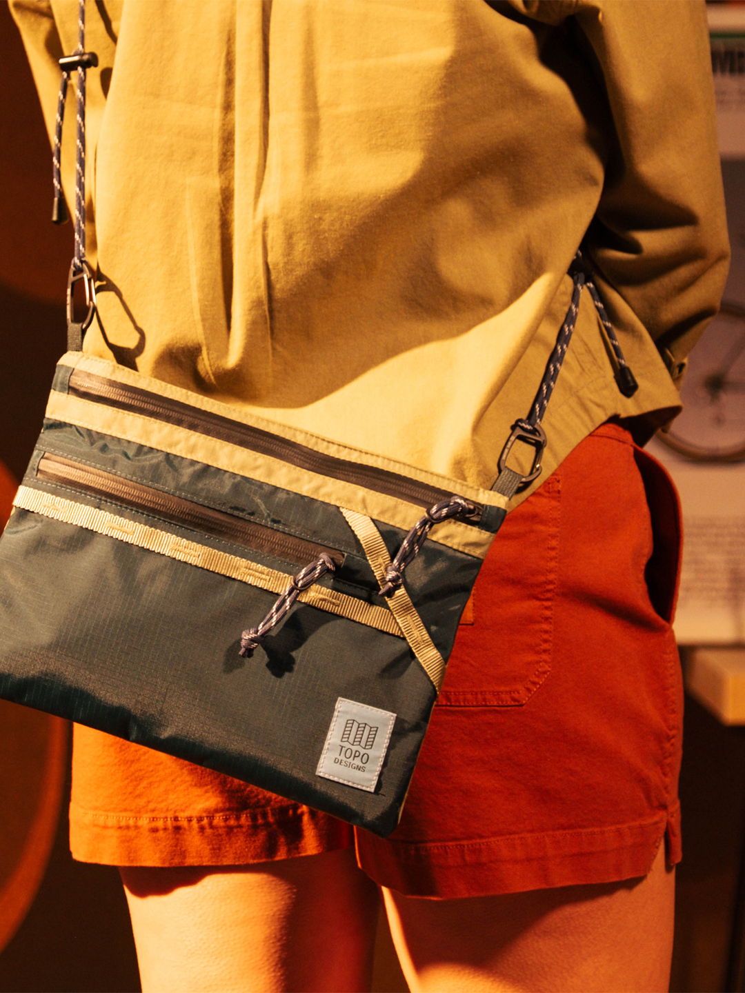 Person wearing a shirt and shorts, holding a stylish crossbody bag.