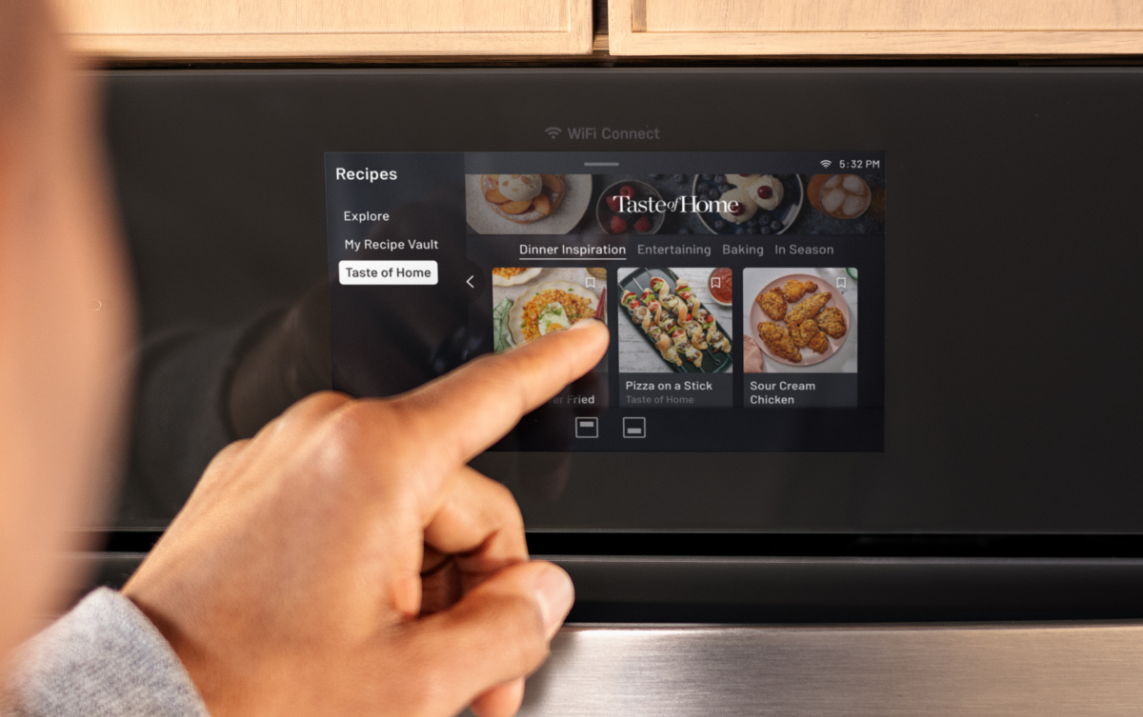 Person interacting with a touchscreen display showing food recipes.