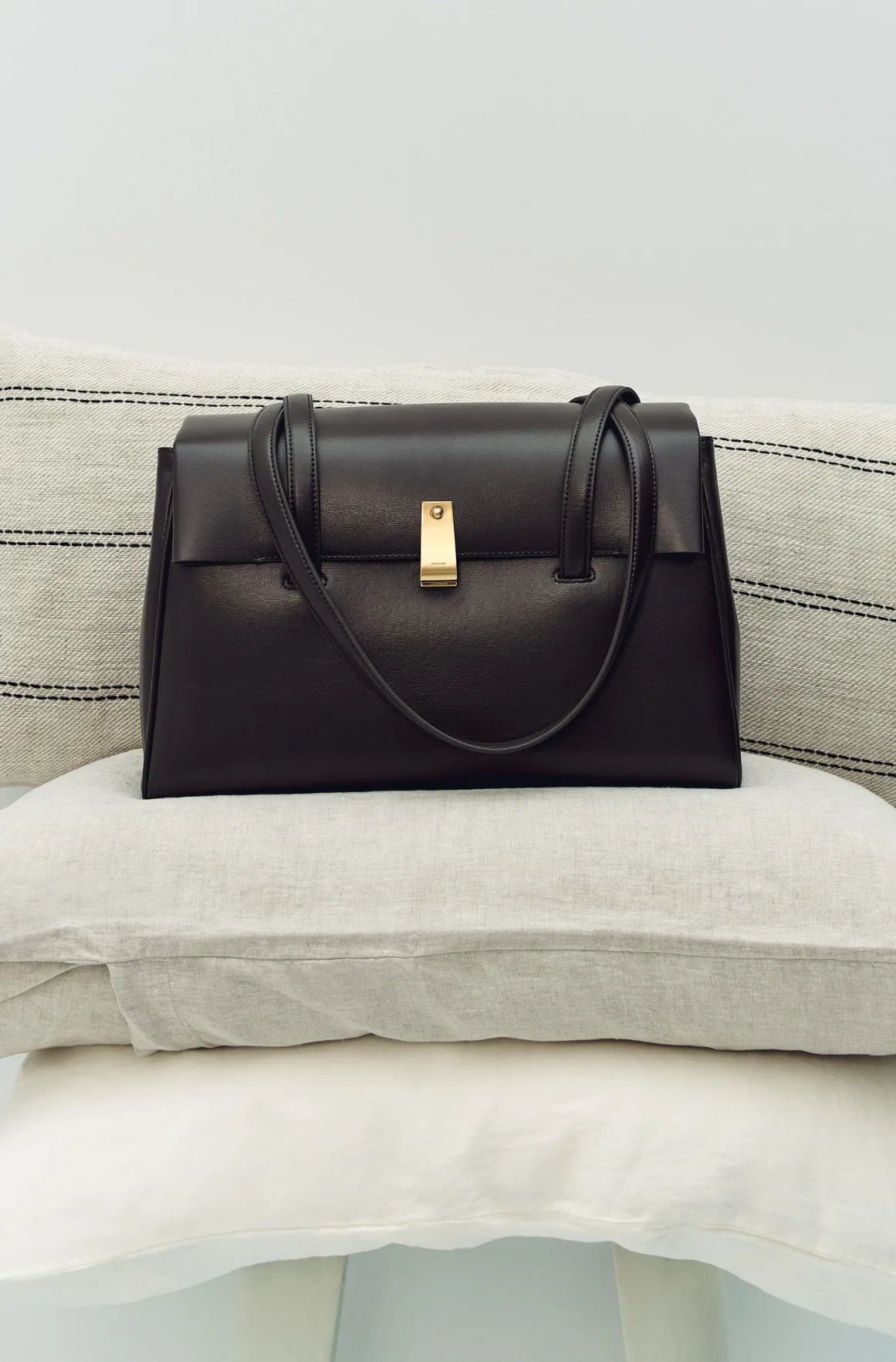 A black handbag resting on stacked cushions.
