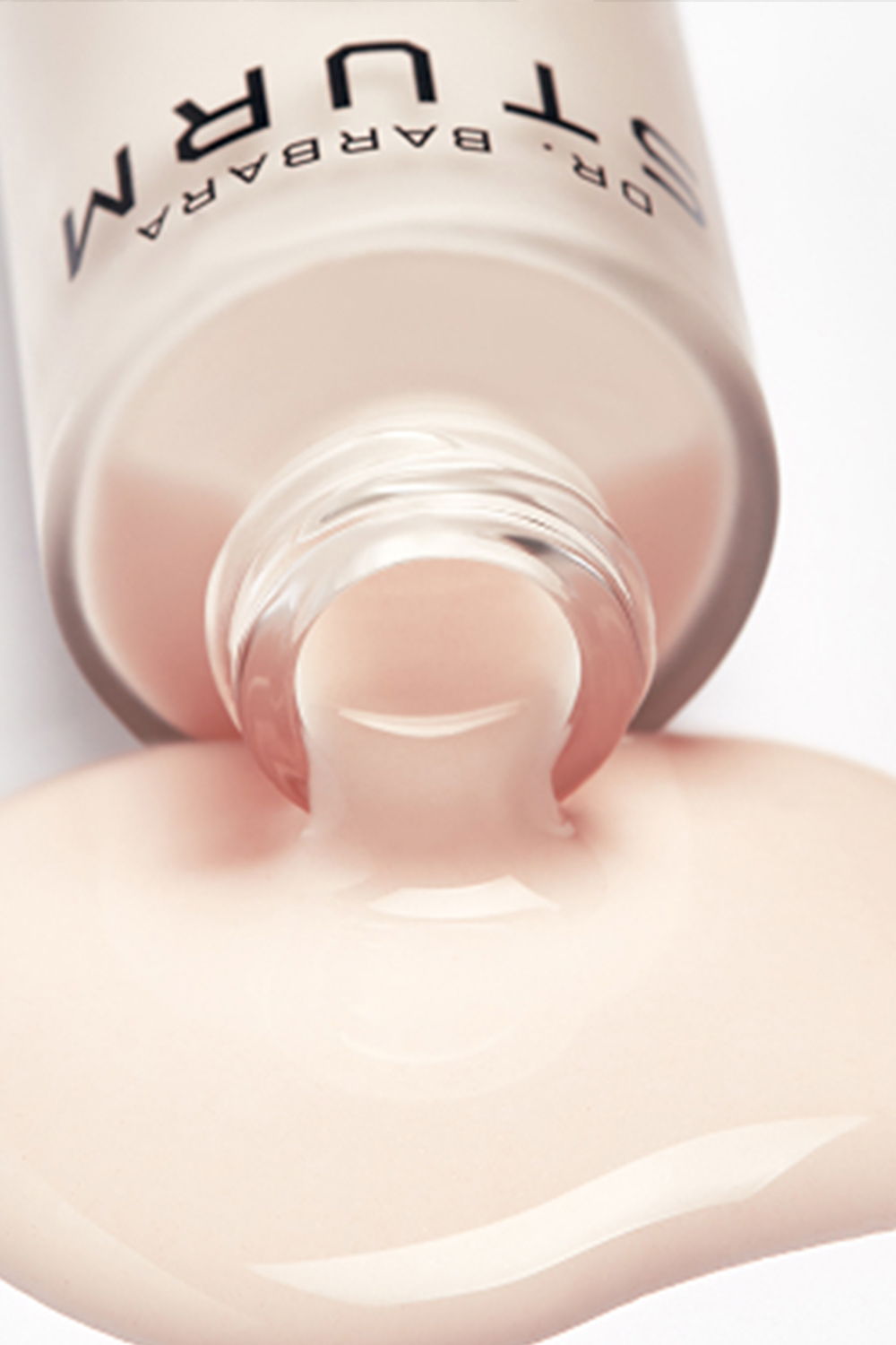 Bottle of pale pink nail polish spilling on a surface.