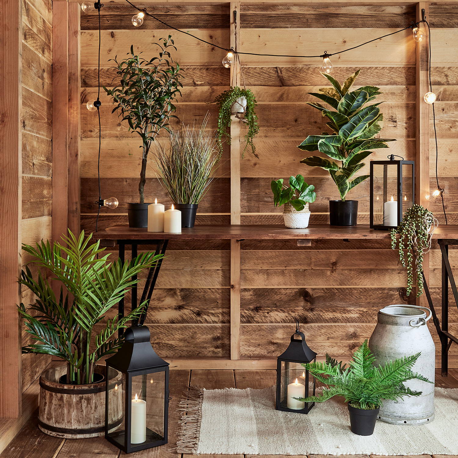 A collection of artificial plants and lanterns in a wooden room.