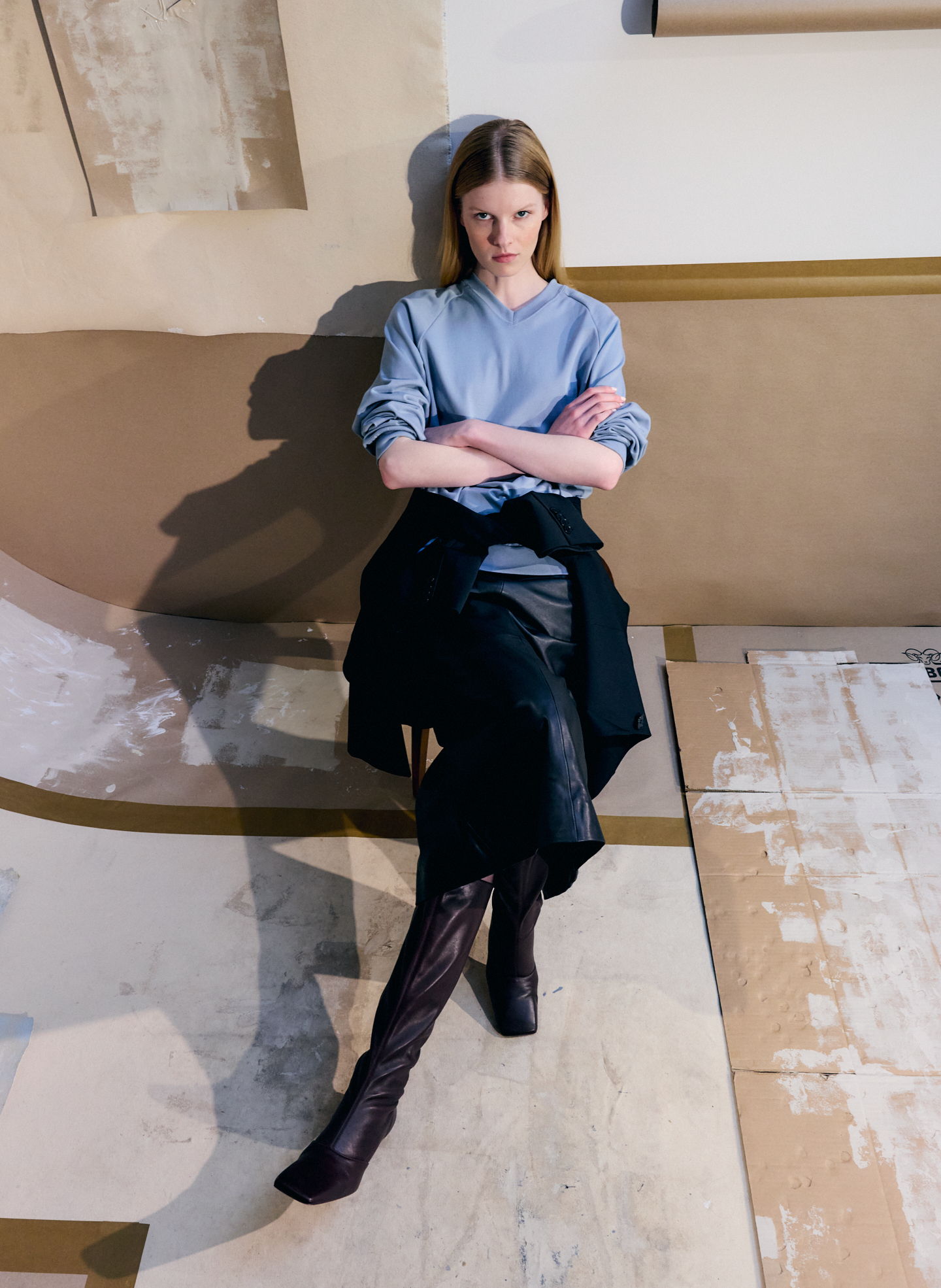 A woman sitting on the floor, wearing a gray top and black skirt.