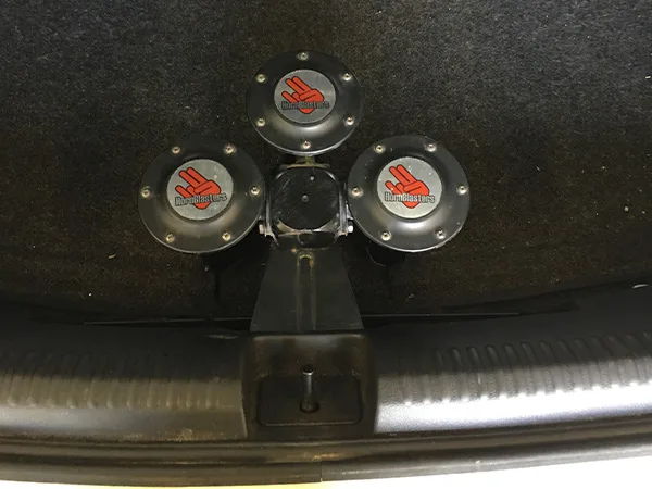 Top-down trunk view of three-horn mount panel on Lauren's white Volkswagen Jetta Rhino 3 Liter horn kit gallery photo 4
