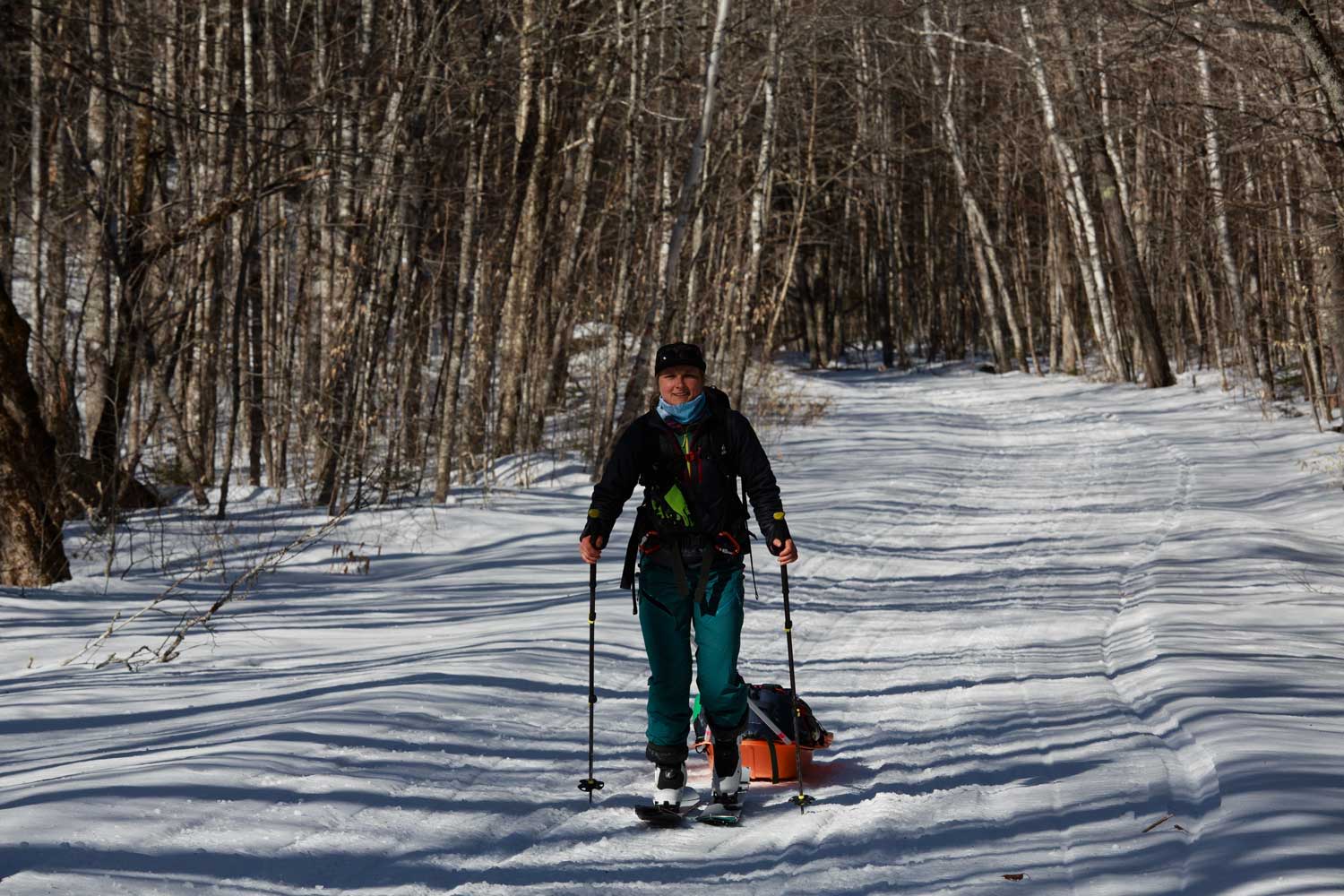 Person splitboarding on a snowy trail surrounded by trees.