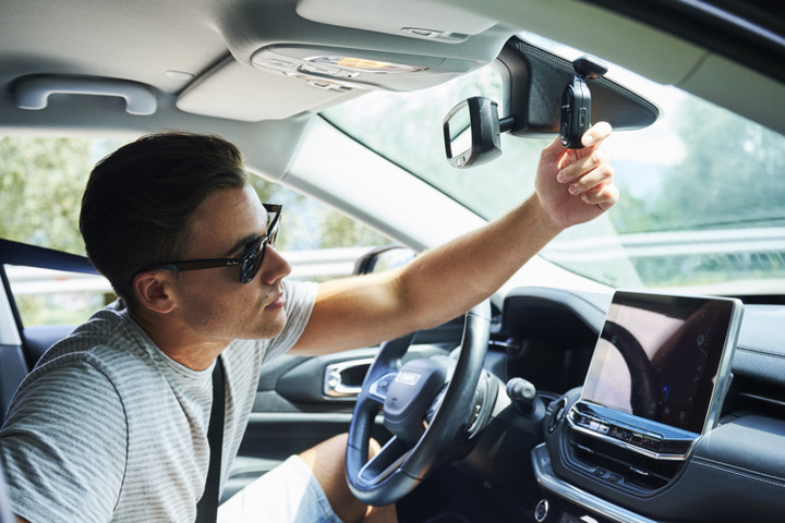 Person adjusting a camera mount inside a car.