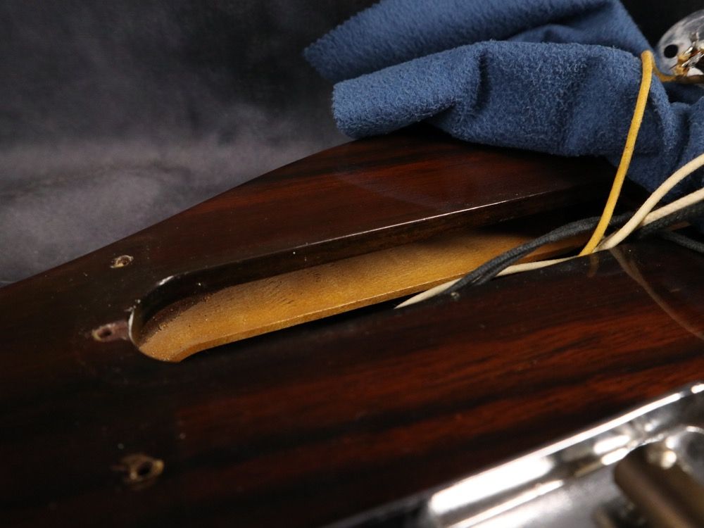 Close-up of a guitar neck cavity with wires and a cloth.