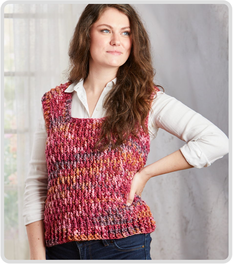 Woman wearing a colorful knitted vest and white shirt, posing confidently.