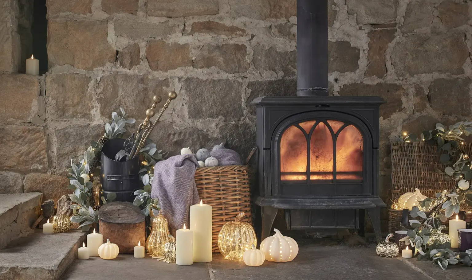 A cosy fireplace setting with pumpkins and LED candles.