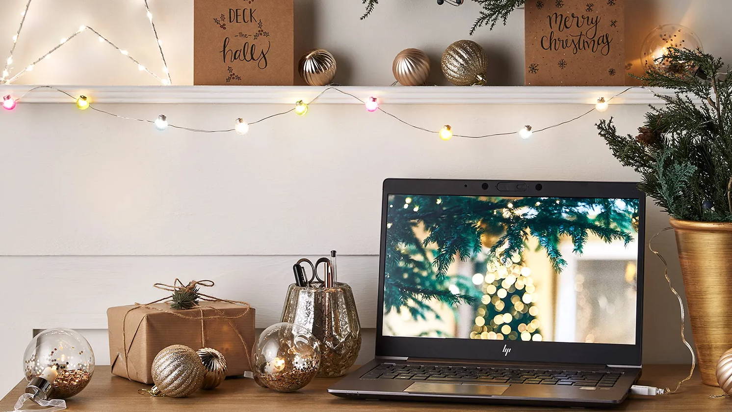 Bunte USB Micro Lichterkette an einem Regal über einem Schreibtisch mit Laptop und Weihnachtsbaumkugeln