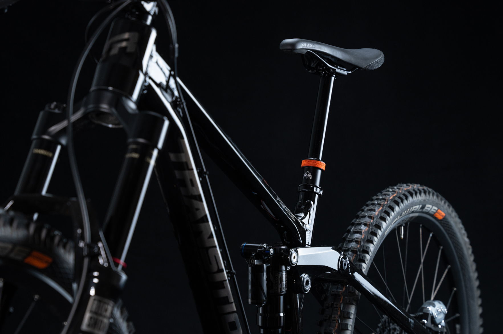 Black mountain bike against a dark background, showcasing details of the frame and seat.