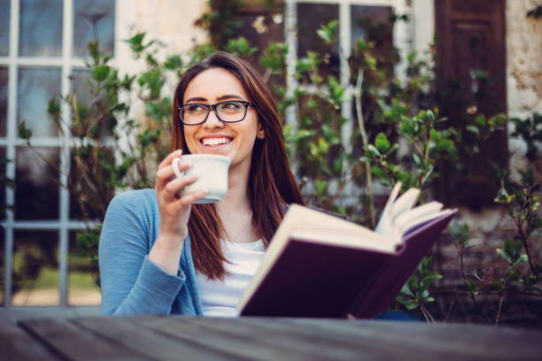 Woman wearing reading glasses and holding a book