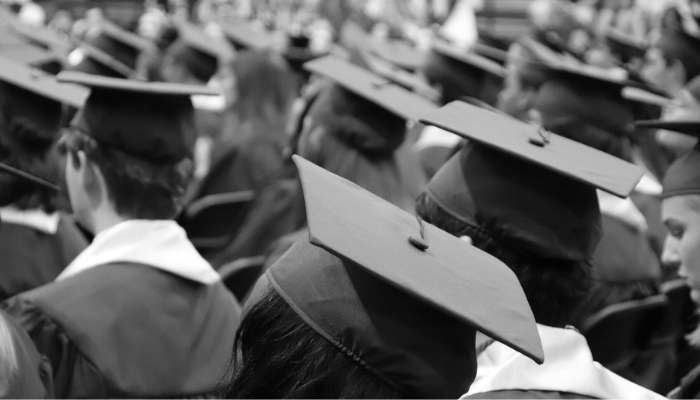 Group of graduates sitting in cap and grown