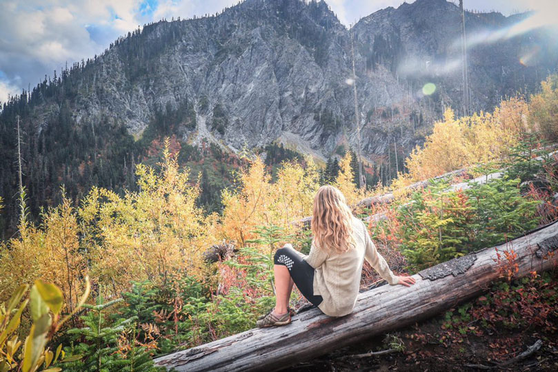 Katelynn sitting on log over looking cascade range mountains.