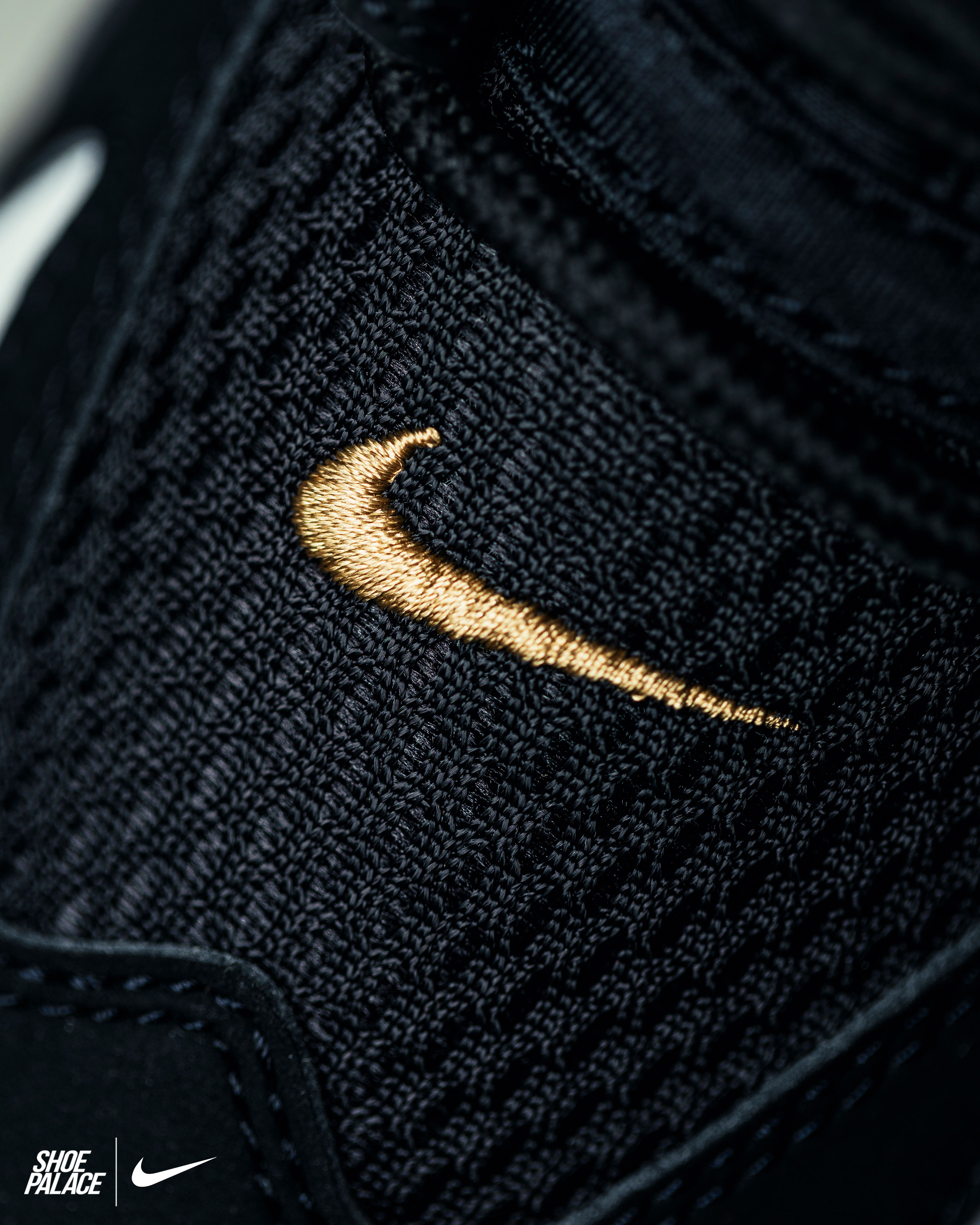 Close-up of a black sneaker with a gold Nike swoosh logo.