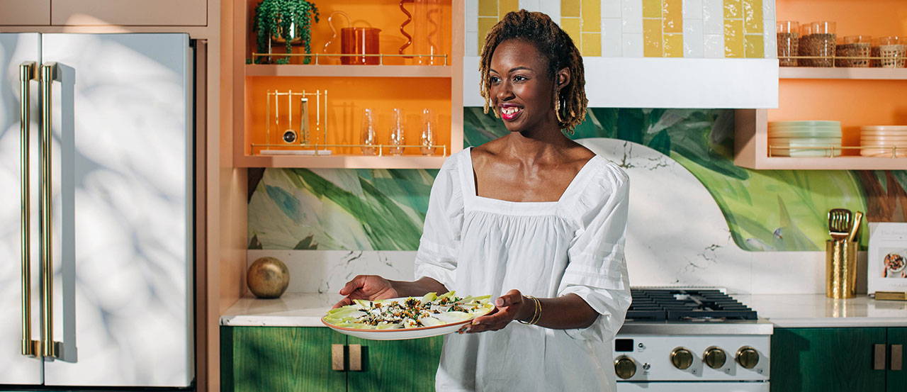 Woman holding up endive salad in matte white kitchen with Brushed Brass hardware