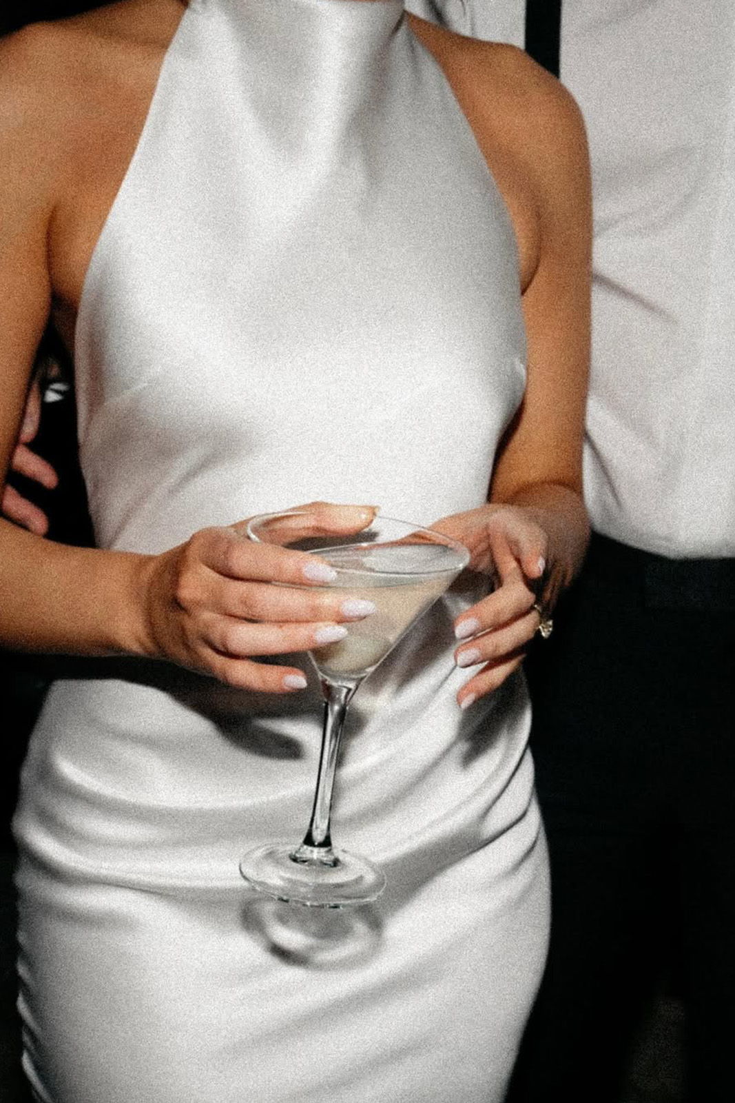 Person in a white dress holding a cocktail glass.