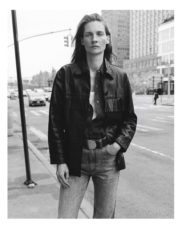 Person in a leather jacket standing on a city street.
