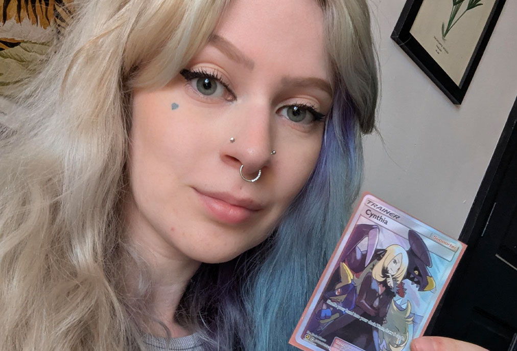 Person with light hair holding a card, smiling at the camera.