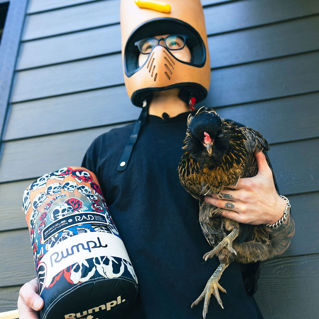 Bryce Wong in a hotdog helmet holding a chicken and a Rumpl blanket.