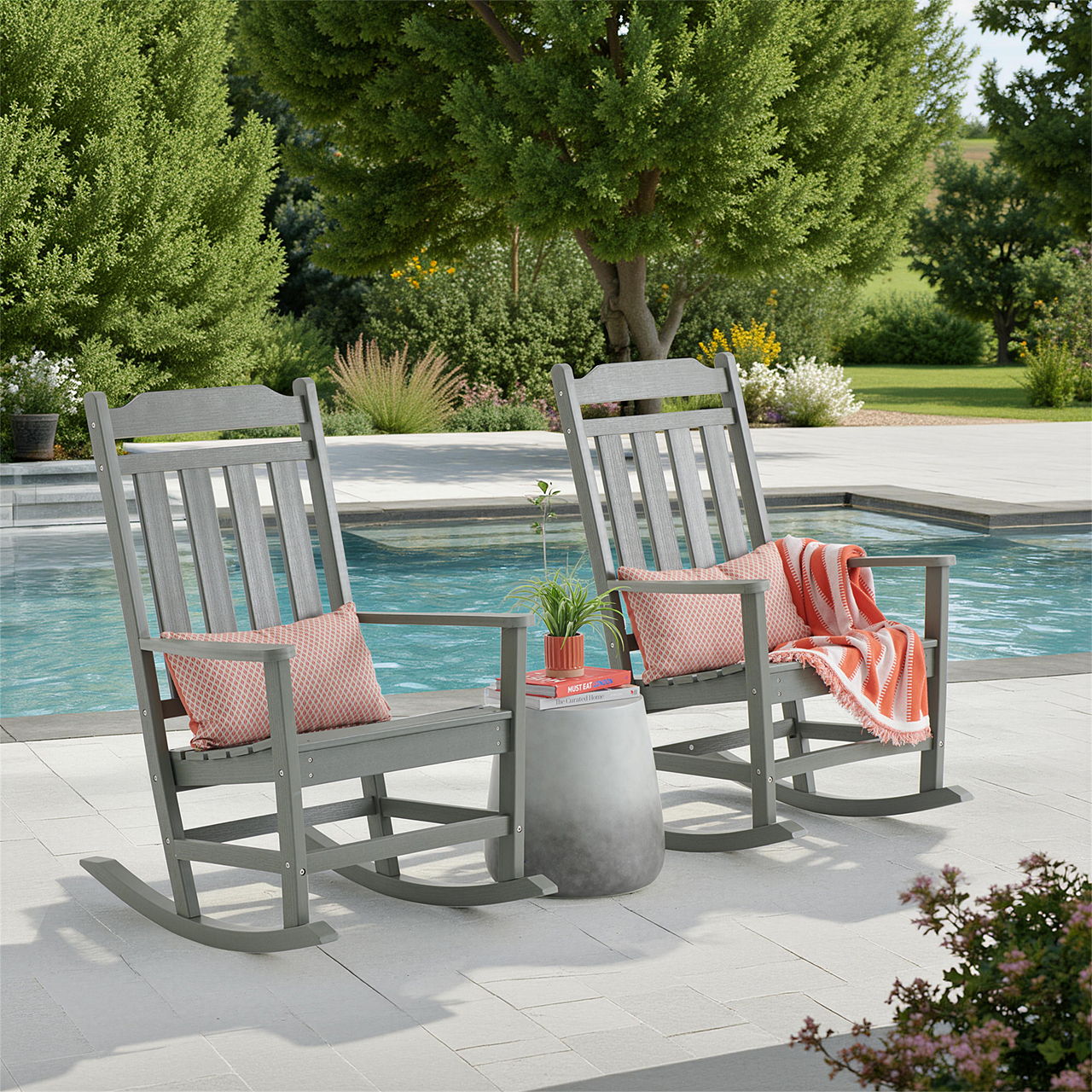 Two rocking chairs by a pool surrounded by greenery and decorative items.