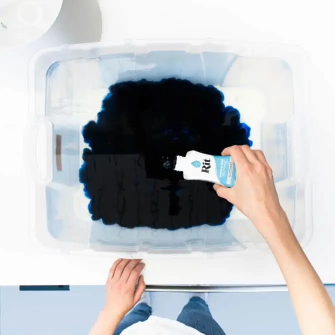 Person adding dye to a water-filled container.