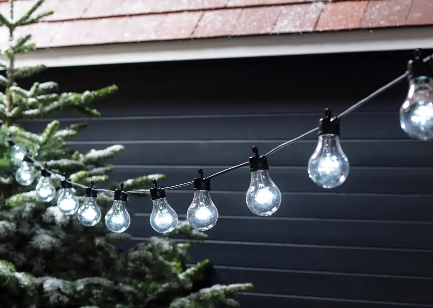60 white led connectable festoon lights on a black cable hanging outdoors