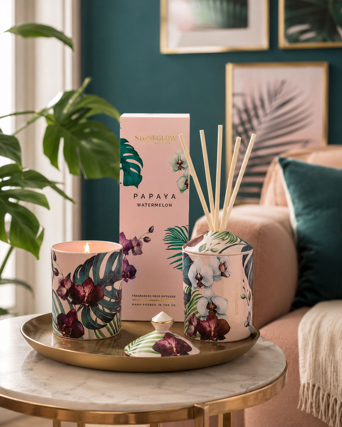 Candle and diffuser on a tray with decorative packaging and plants.