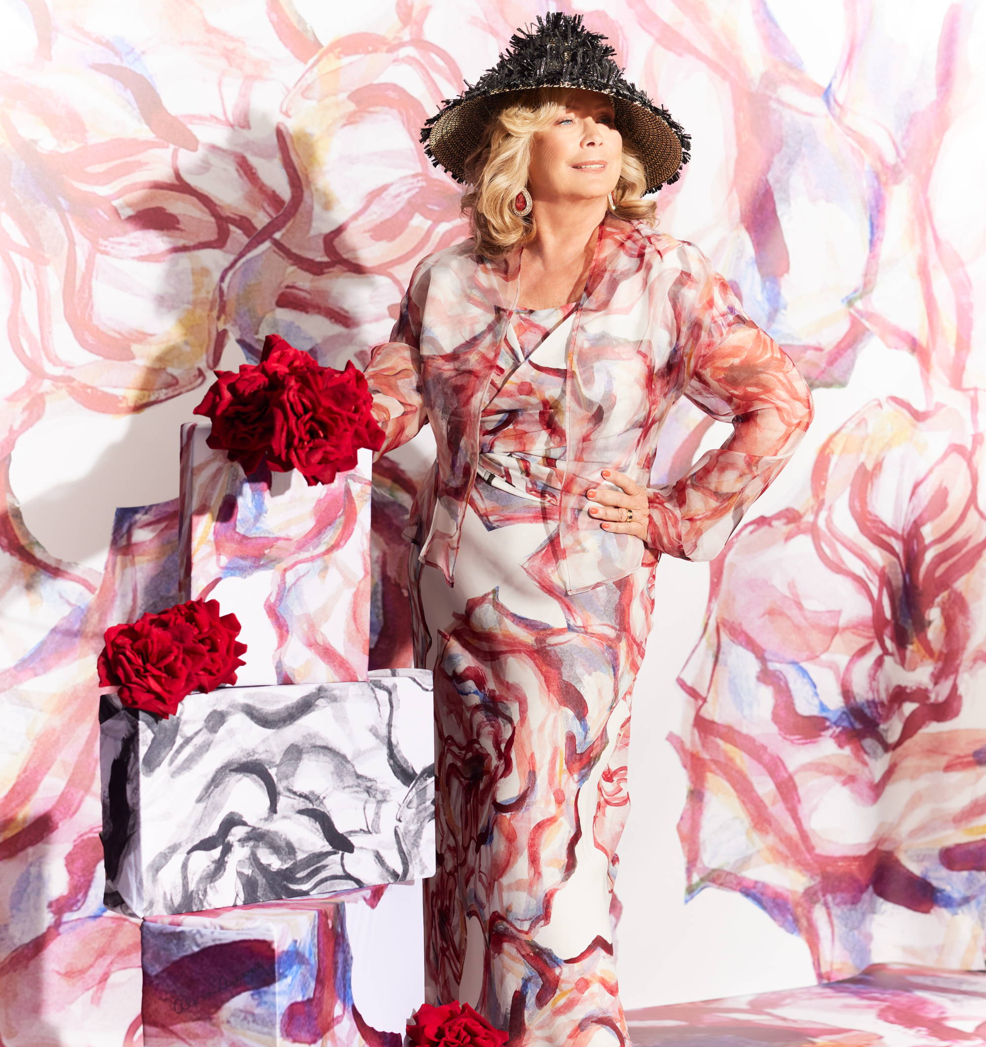 Ala Isham wearing rose printed silk slip dress with organza jacket and hat with christmas presents | holiday hint list