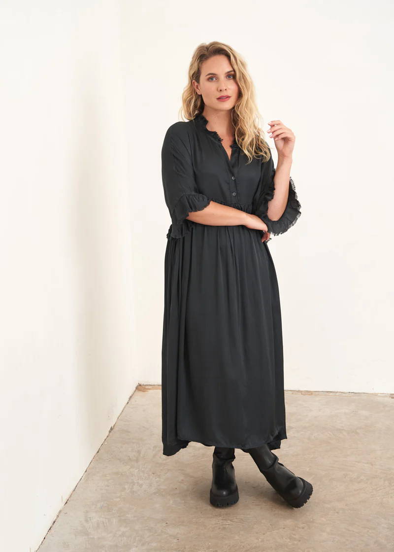 A model wearing an oversized satin dress with 3/4 sleeves and frill detail
