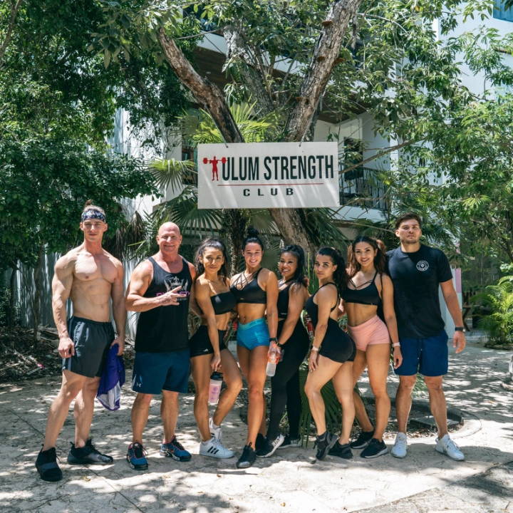A group of athletic people joined with Stephanie Ayala McHugh posing in front of Tulum Strength Club 