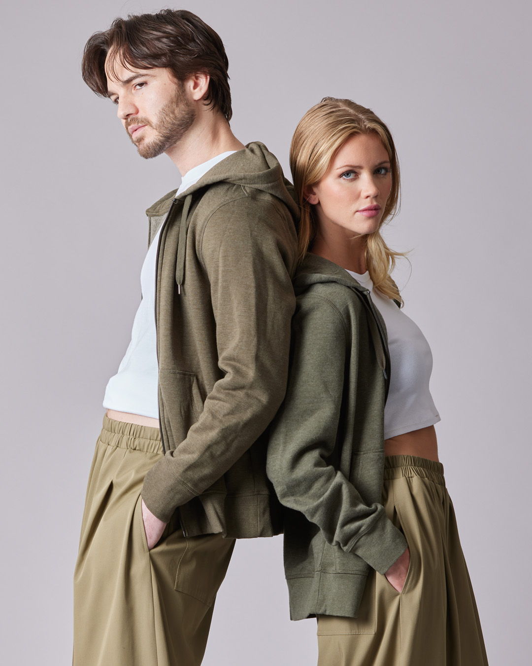 Two models in casual outfits standing back to back.