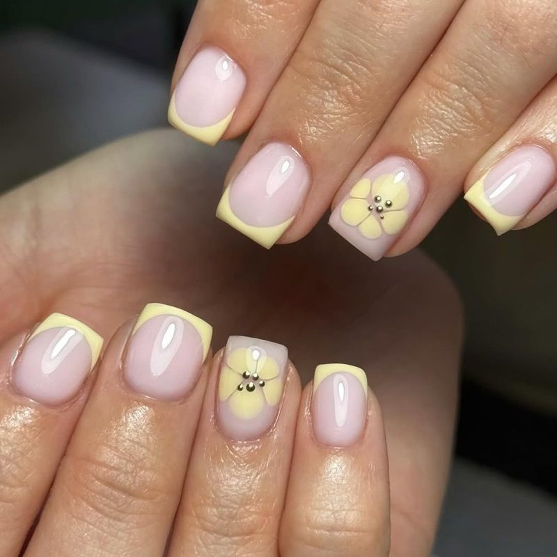 Nails with pink polish and yellow tips, featuring decorative designs.