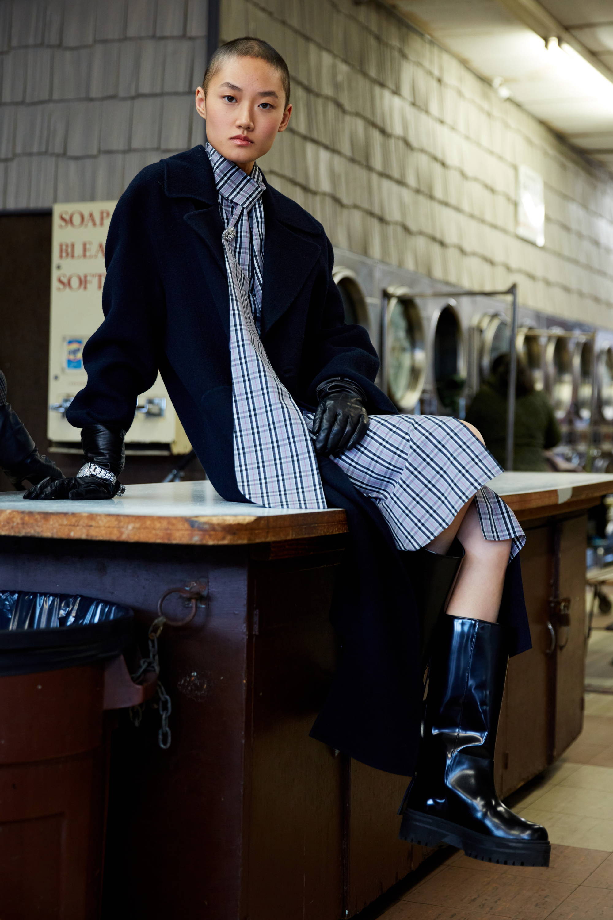 A model in a stylish outfit poses at a laundromat.