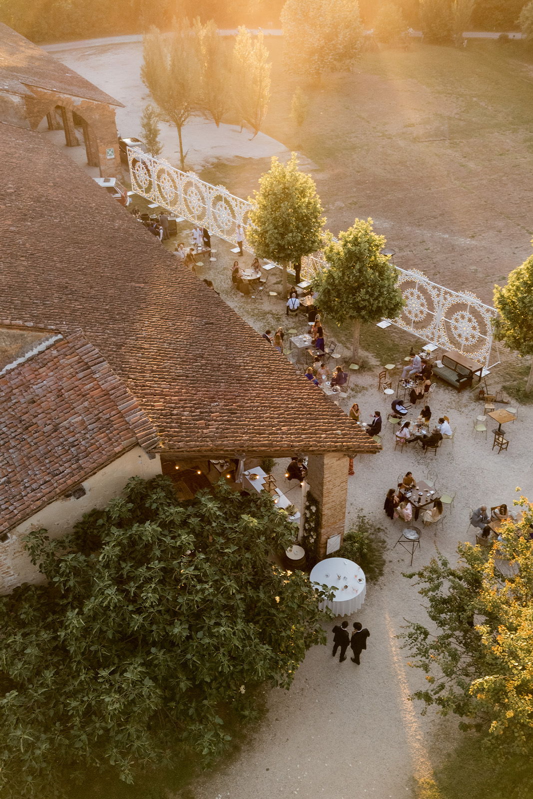 Aerial view of a gathering near a rustic building during sunset.
