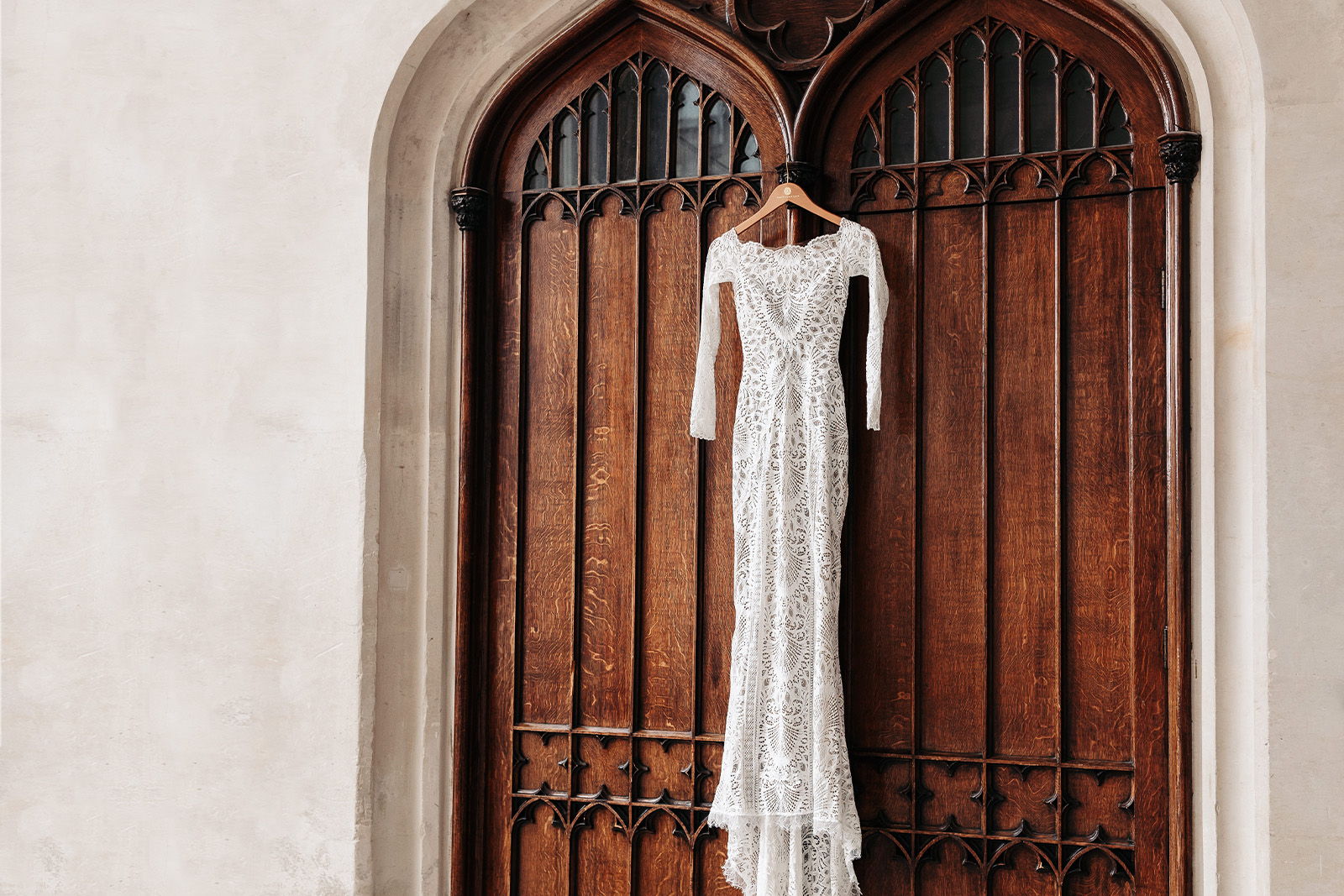 A white wedding dress hanging on a wooden door.