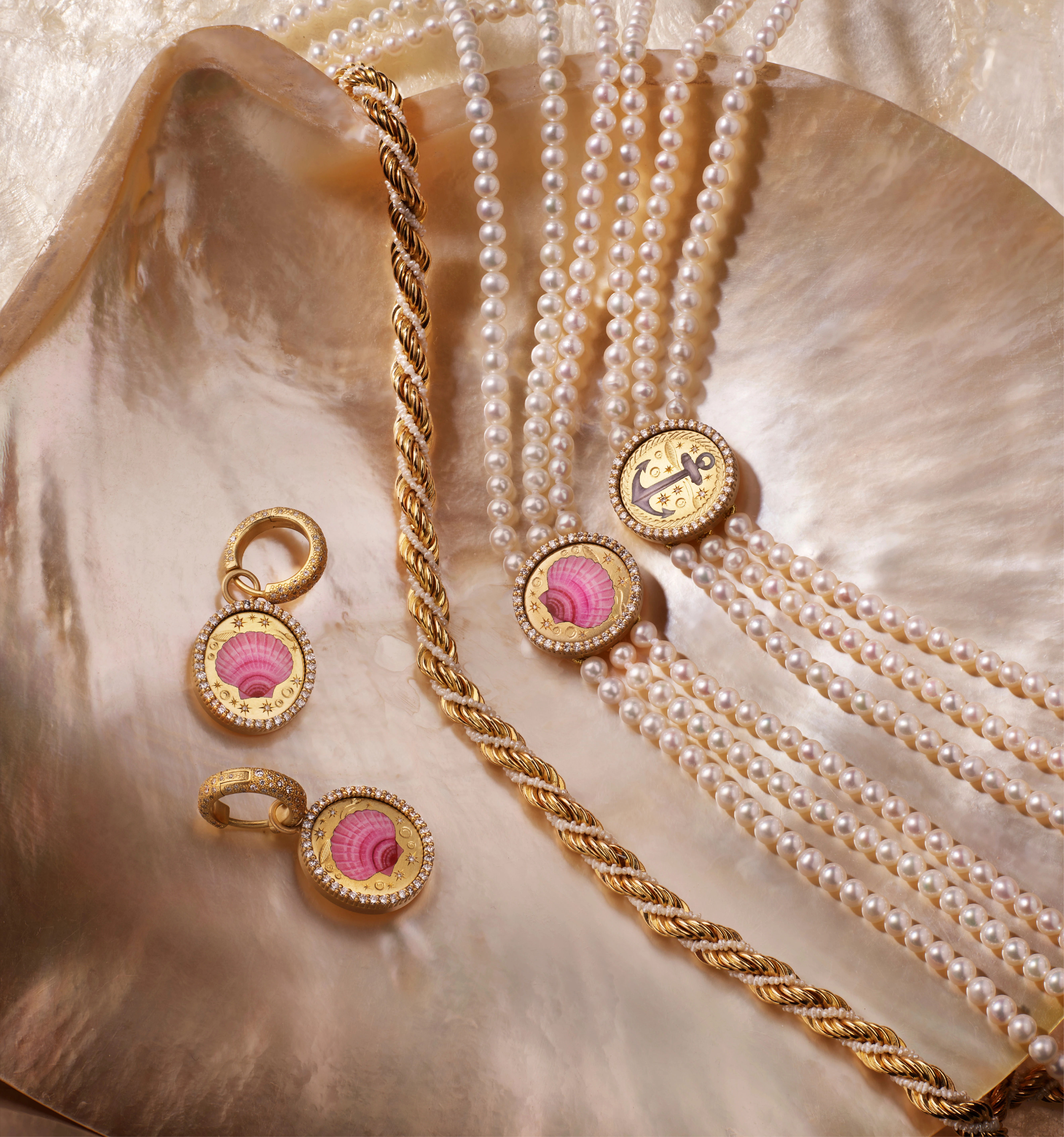 Elegant jewelry set displayed on a seashell, featuring gold and pink accents.