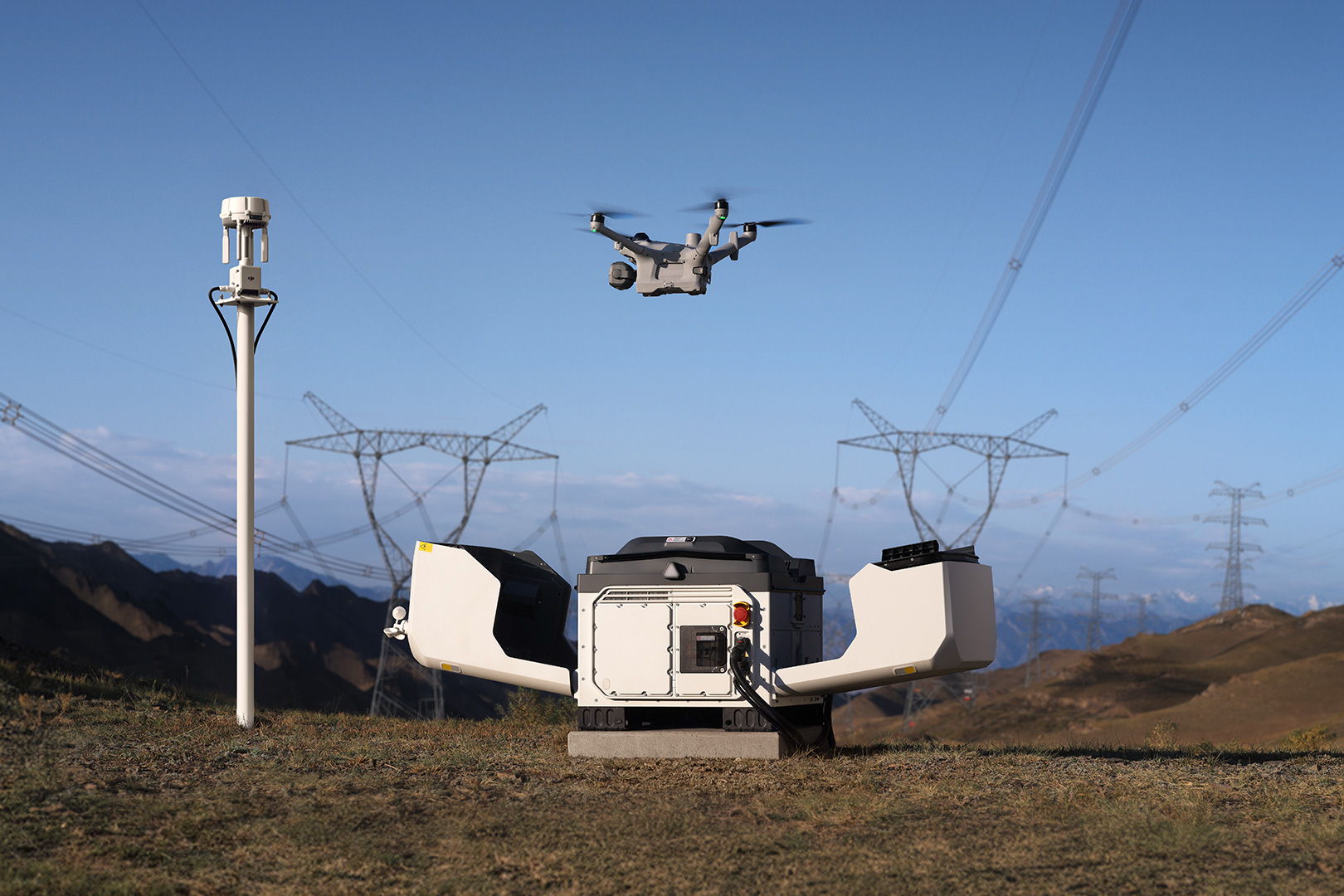 A DJI Matrice 5TD drone flying above a DJI Dock 4 in an outdoor landscape.