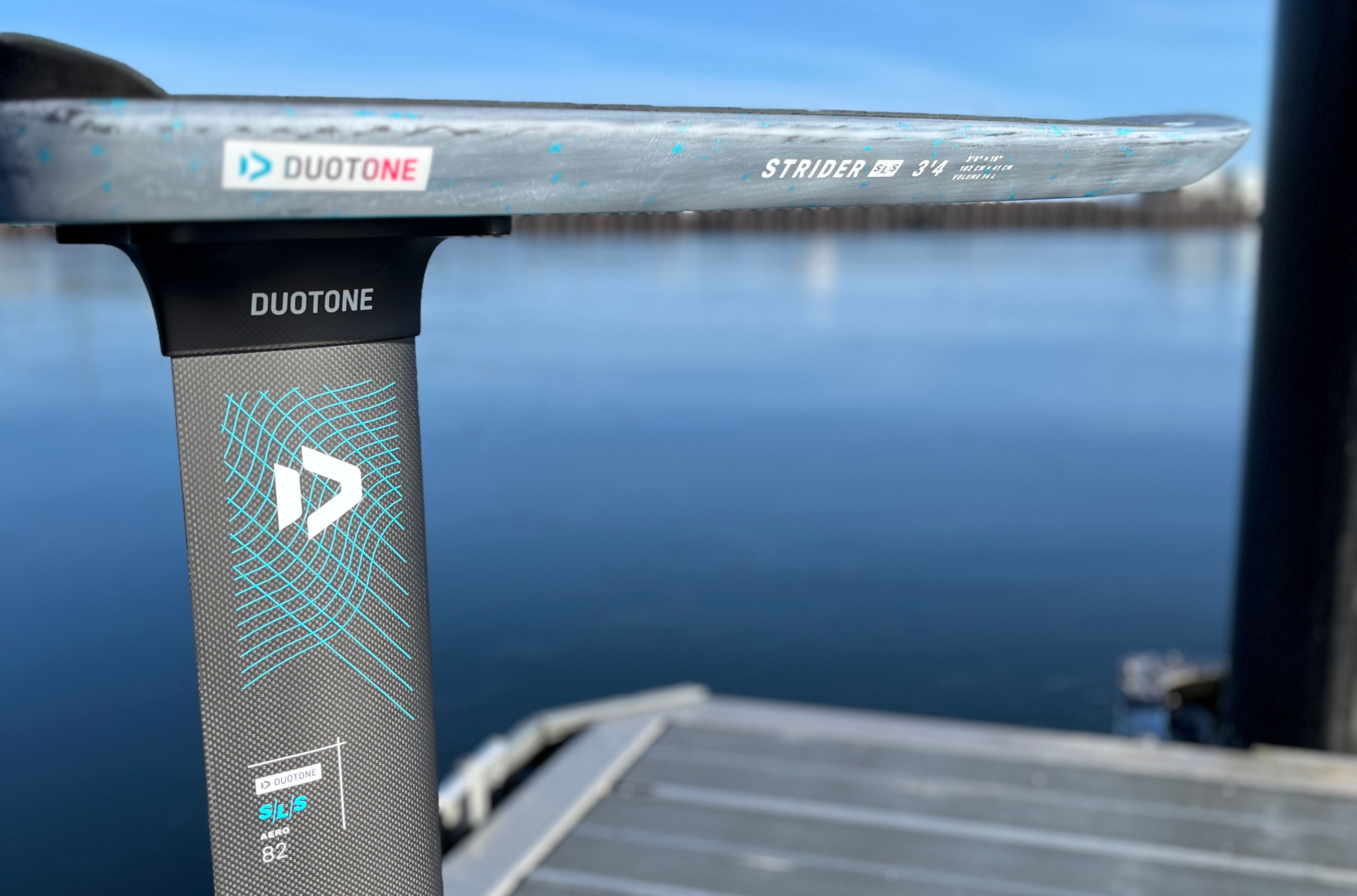 Close-up of a scooter deck near water with reflections.