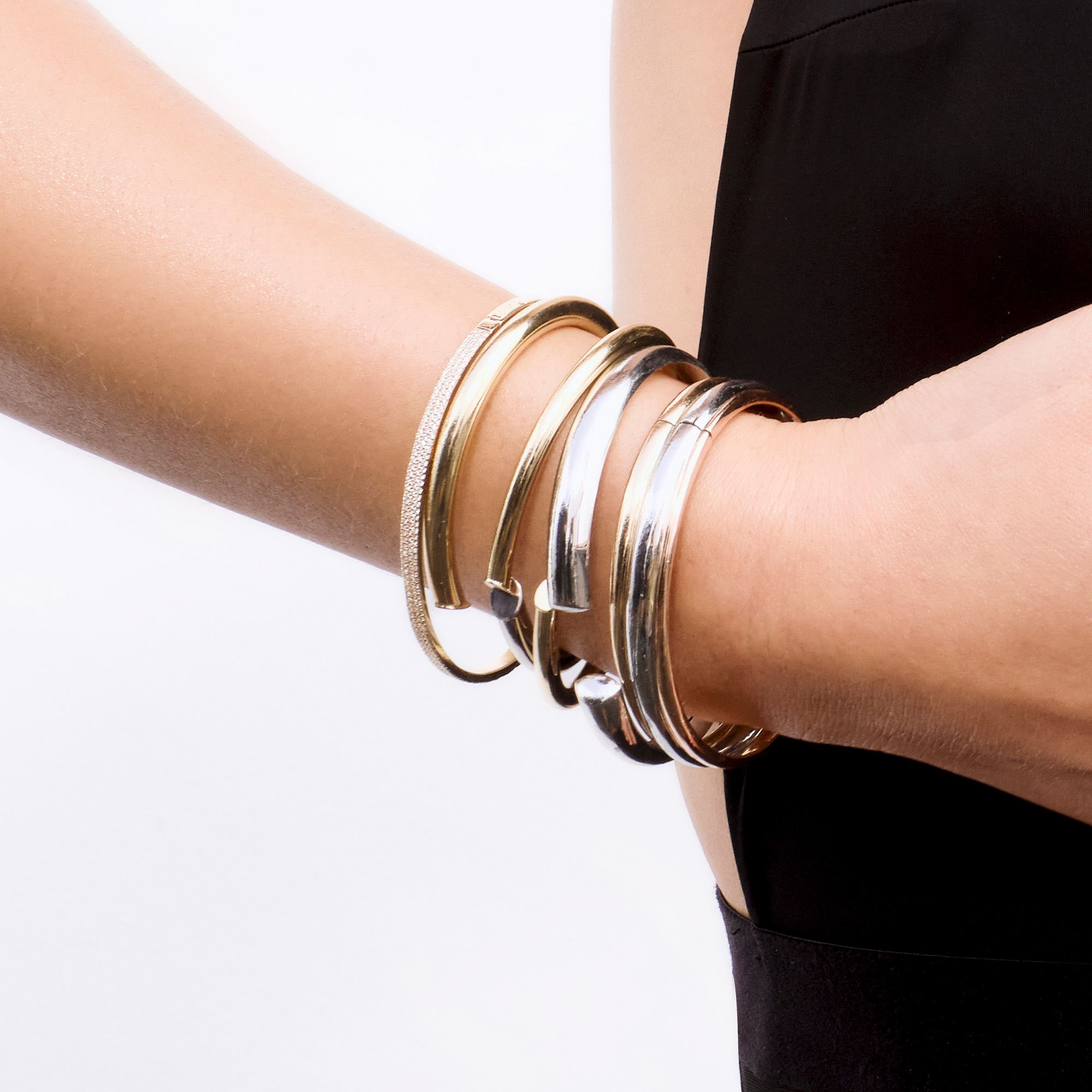 A close-up of a wrist adorned with multiple metallic bangles.
