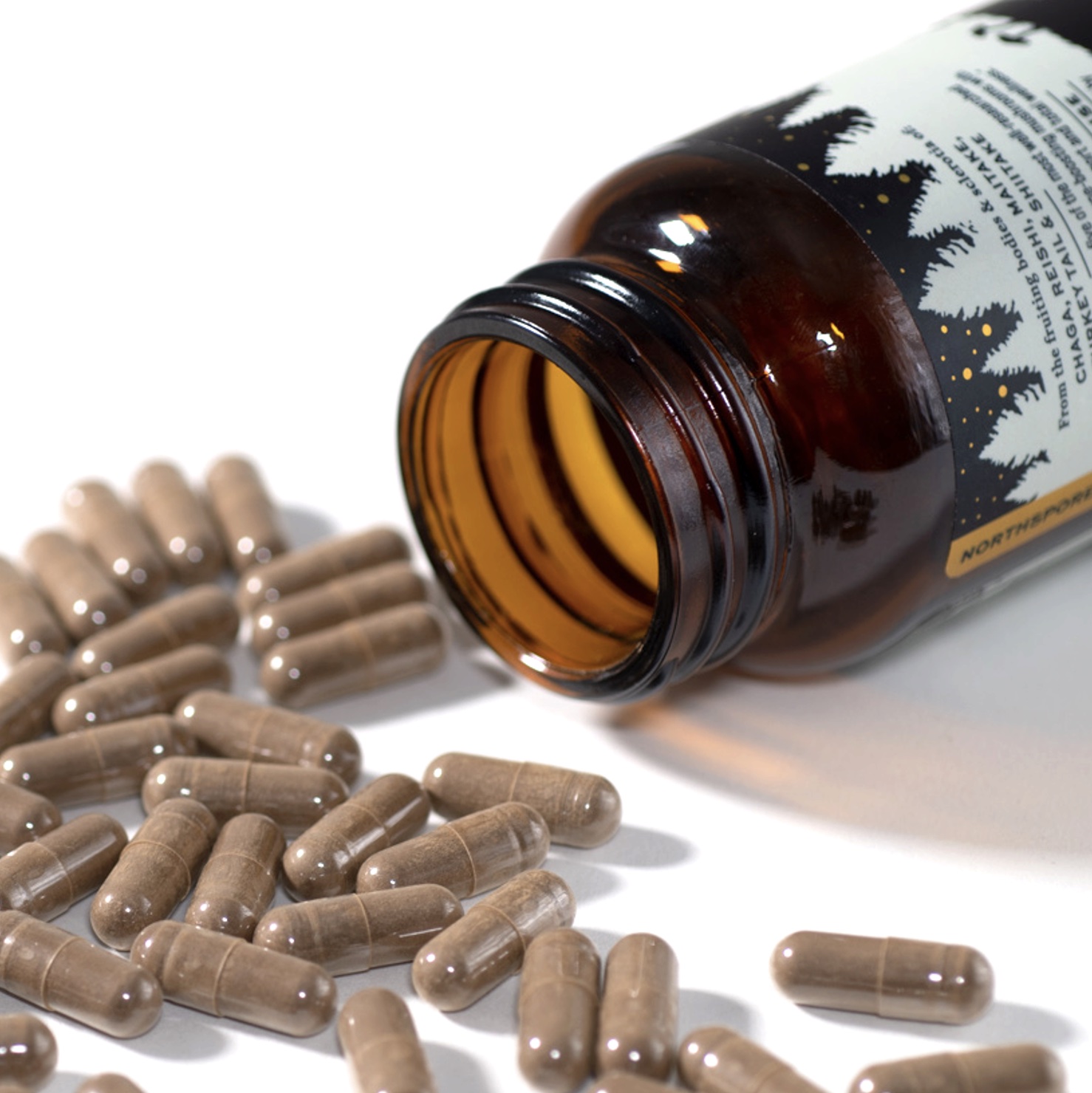 Brown bottle with capsules spilled on a white surface.
