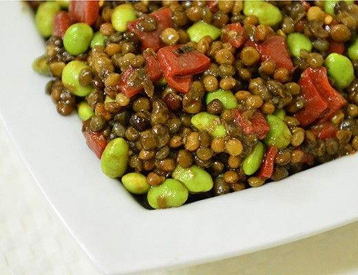 Bowl of lentils with vegetables, including edamame and diced peppers.